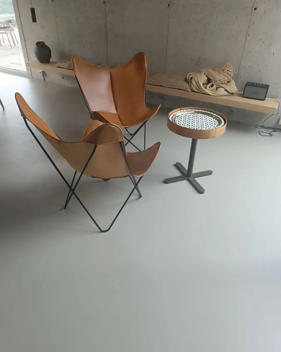 Saumaton mikrosementtilattia olohuoneessa, taustalla betoniseinä.