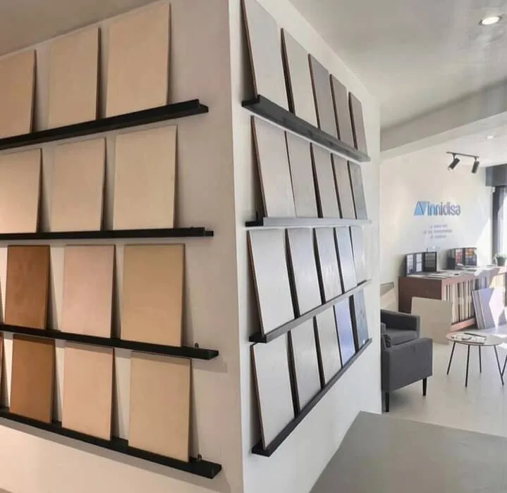 Seinällinen mikrosementtimallipaloja eri sävyissä, taustalla showroomin oleskelutila.