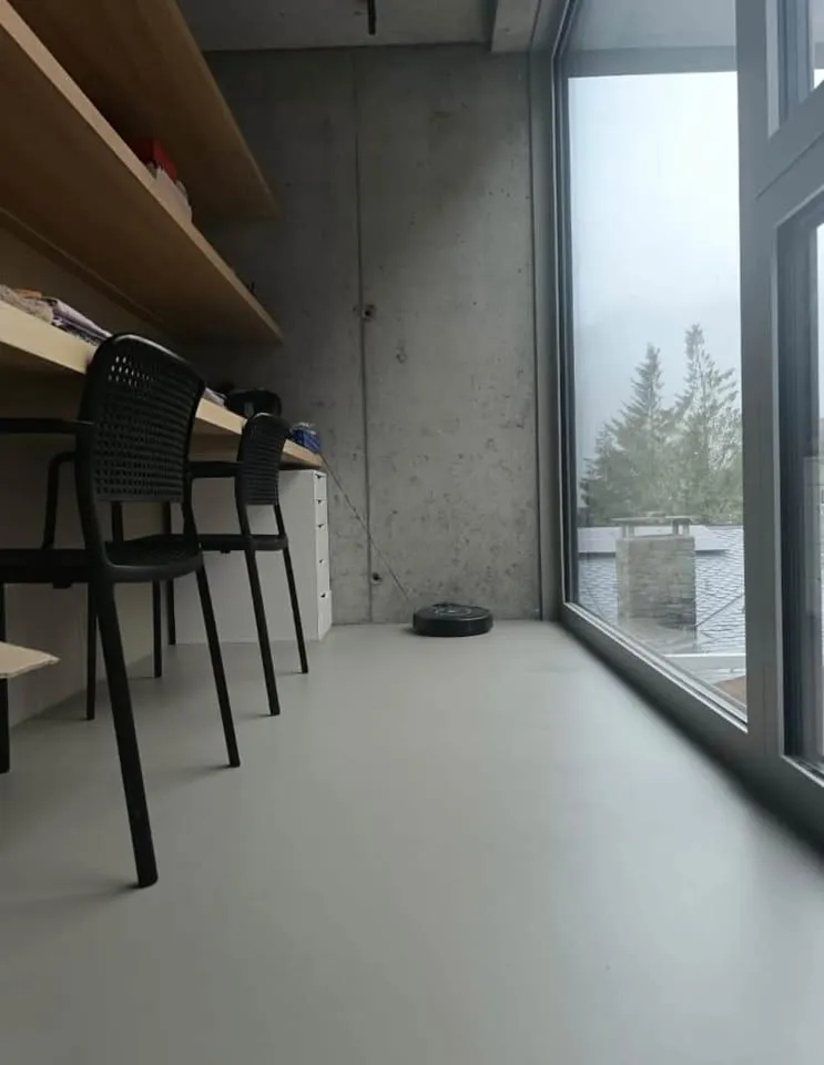 Työtila, jossa paljas betoniseinä ja mikrosementtilattia ovat vierekkäin.